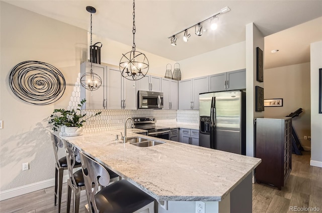 5401 S Park Terrace Ave Unit 109A, Greenwood Village, CO 80111 - kitchen with stainless steel appliances, a peninsula, light stone countertops, wood finished floors, and backsplash