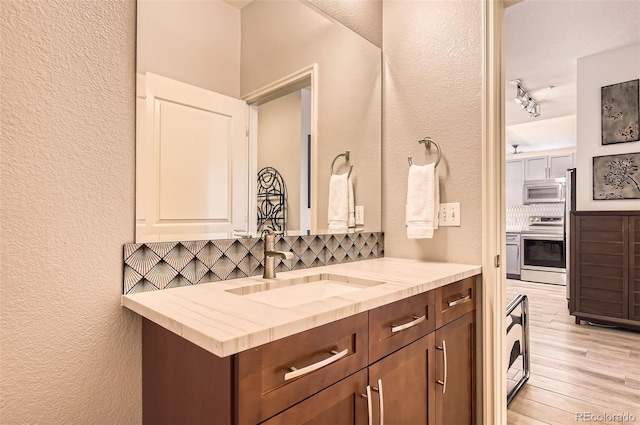 5401 S Park Terrace Ave Unit 109A, Greenwood Village, CO 80111 - bathroom with tasteful backsplash, a textured wall, wood finished floors, and vanity