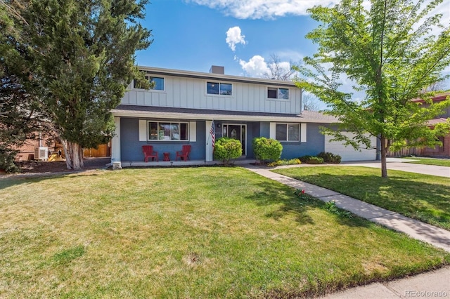 traditional-style home featuring a porch, a front lawn, an attached garage, and concrete driveway