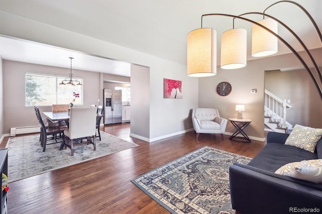 living room with baseboard heating, baseboards, an inviting chandelier, and wood finished floors