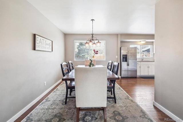dining space with baseboards, a notable chandelier, and dark wood finished floors