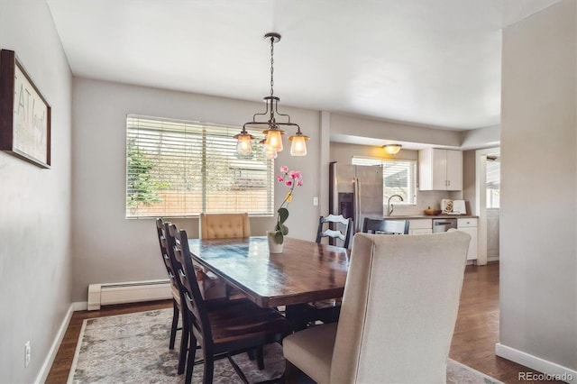 dining area with baseboards, a baseboard radiator, wood finished floors, and a notable chandelier