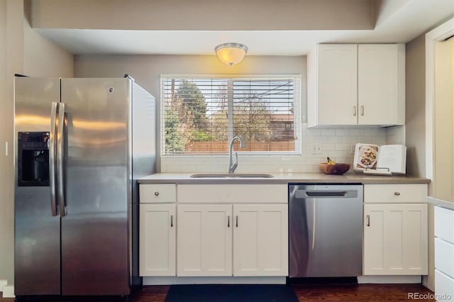 kitchen with a sink, appliances with stainless steel finishes, backsplash, and white cabinetry