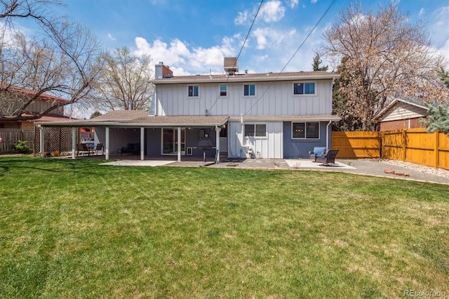 back of property featuring a fenced backyard, a chimney, a lawn, and a patio area