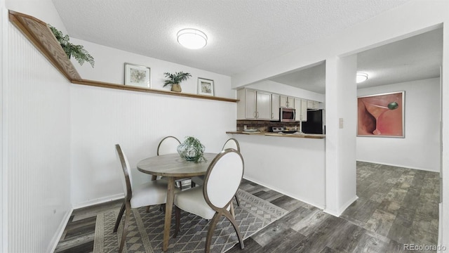 dining area with a textured ceiling and dark wood-type flooring