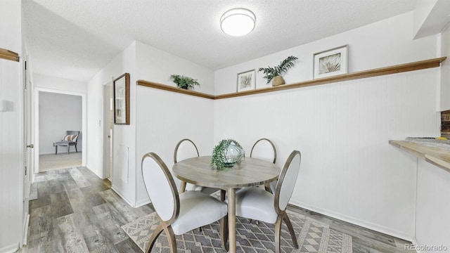 dining room featuring wood-type flooring and a textured ceiling