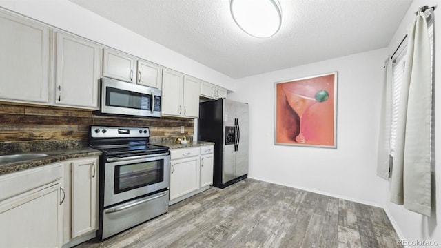 kitchen featuring white cabinetry, a textured ceiling, stainless steel appliances, and light wood-type flooring