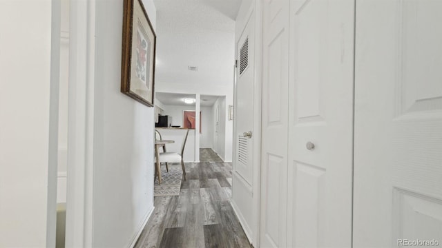 corridor featuring a textured ceiling and hardwood / wood-style floors