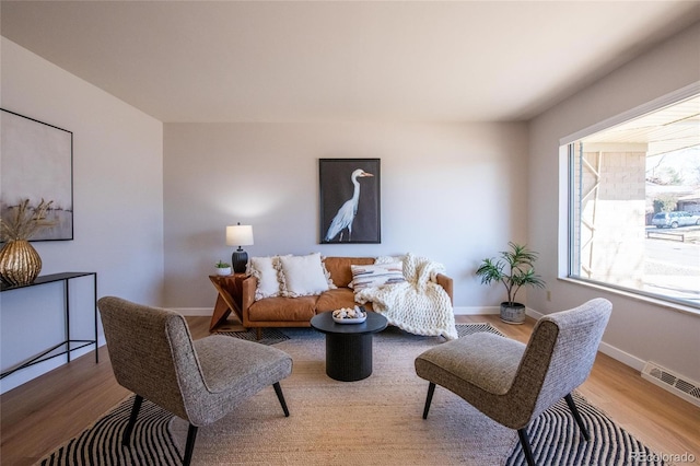 living room with visible vents, baseboards, and wood finished floors