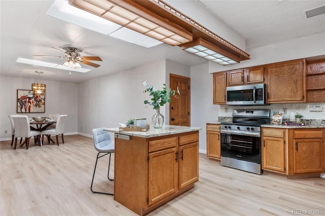 kitchen with stainless steel appliances, open shelves, a center island, and light wood-style floors