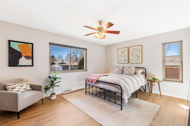 bedroom with light wood finished floors, baseboards, visible vents, and a ceiling fan