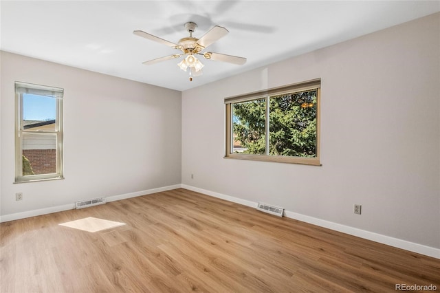 spare room featuring a healthy amount of sunlight, visible vents, and baseboards