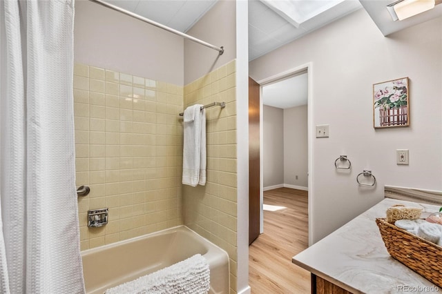 bathroom with a skylight, shower / tub combo with curtain, baseboards, and wood finished floors