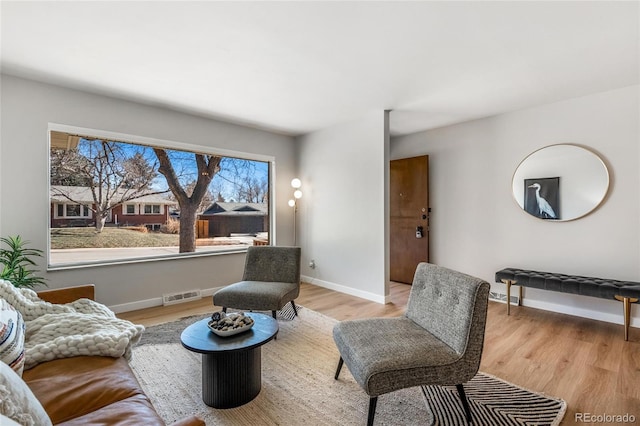 living area with baseboards, visible vents, and light wood finished floors