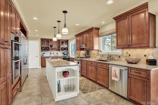 kitchen with sink, hanging light fixtures, a center island with sink, stainless steel appliances, and light stone countertops