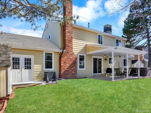 7631 Oak St, Arvada, CO 80005 - back of property featuring a chimney, a patio area, a yard, and a shingled roof