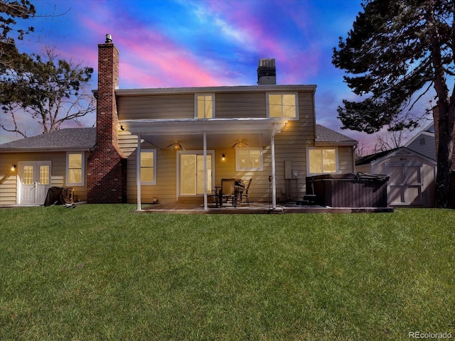7631 Oak St, Arvada, CO 80005 - back of house at dusk featuring a chimney, a storage unit, a patio, and a lawn