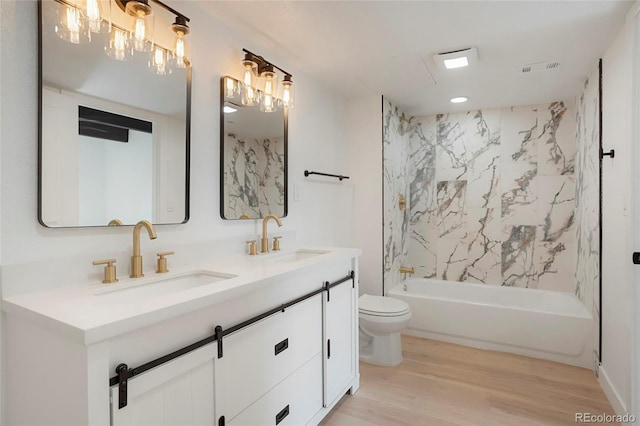 full bathroom featuring vanity, wood-type flooring, tiled shower / bath combo, and toilet