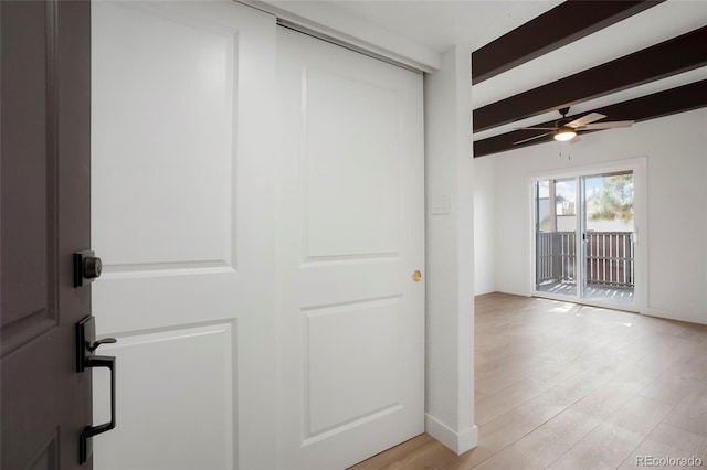 hallway featuring beamed ceiling and light hardwood / wood-style floors