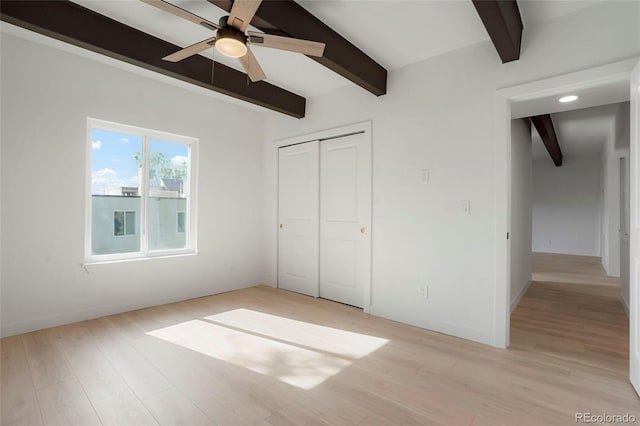 unfurnished bedroom featuring ceiling fan, a closet, beamed ceiling, and light hardwood / wood-style floors