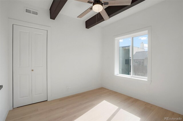 unfurnished bedroom with beamed ceiling, a closet, ceiling fan, and light hardwood / wood-style floors