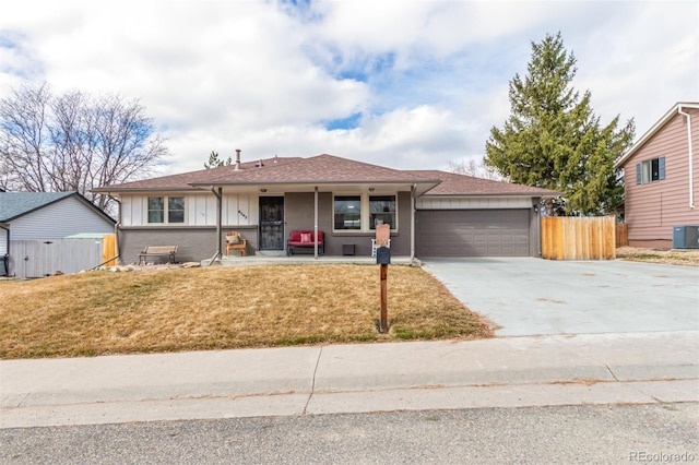 view of front of property featuring a front yard, concrete driveway, fence, and an attached garage