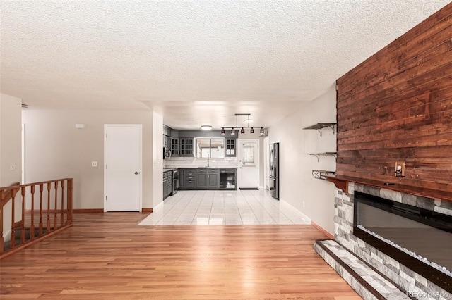 unfurnished living room featuring wine cooler, a large fireplace, a sink, and light wood finished floors