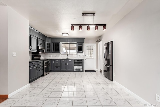 kitchen with marble finish floor, stainless steel appliances, gray cabinets, glass insert cabinets, and a sink