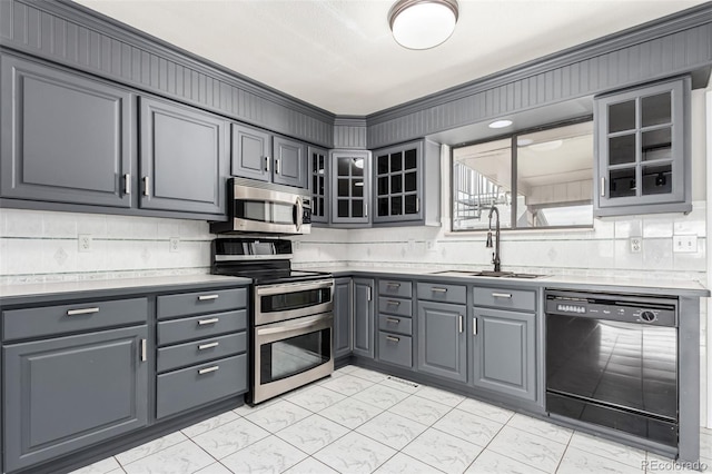 kitchen featuring appliances with stainless steel finishes, marble finish floor, a sink, and gray cabinetry