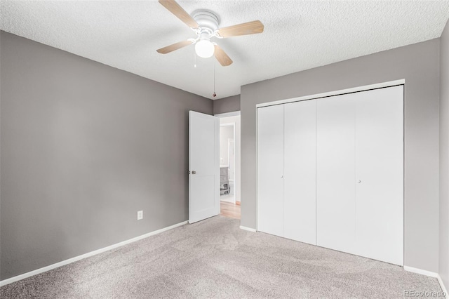 unfurnished bedroom with carpet, a closet, a textured ceiling, and baseboards