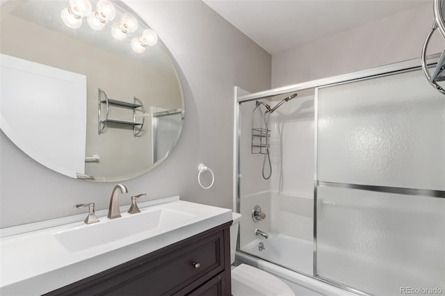 full bath featuring toilet, shower / bath combination with glass door, and vanity