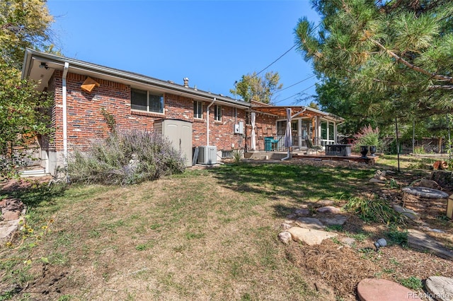 rear view of property with cooling unit and a lawn