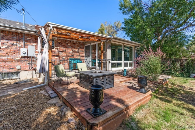 rear view of house with a wooden deck, an outdoor fire pit, and a sunroom