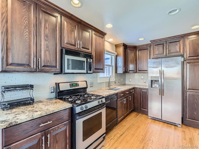 kitchen featuring sink, light hardwood / wood-style flooring, appliances with stainless steel finishes, dark brown cabinets, and light stone counters