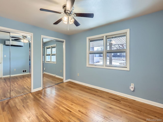 unfurnished bedroom with ceiling fan, two closets, and multiple windows