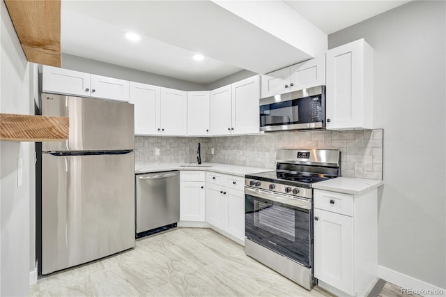 kitchen with white cabinets, appliances with stainless steel finishes, decorative backsplash, and sink