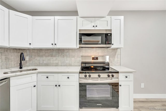 kitchen with appliances with stainless steel finishes, tasteful backsplash, white cabinets, and sink