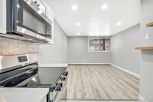 kitchen featuring appliances with stainless steel finishes, light hardwood / wood-style floors, decorative backsplash, white cabinetry, and a baseboard radiator