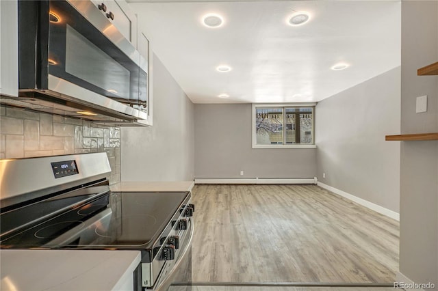 kitchen with baseboard heating, tasteful backsplash, light hardwood / wood-style flooring, and appliances with stainless steel finishes