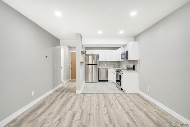 kitchen featuring light hardwood / wood-style flooring, tasteful backsplash, white cabinets, appliances with stainless steel finishes, and sink