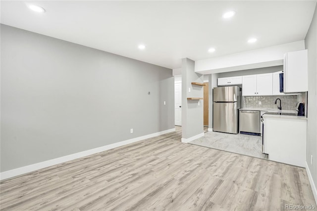 kitchen with light hardwood / wood-style flooring, stainless steel appliances, backsplash, and white cabinetry