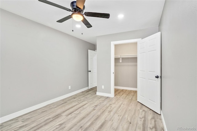 unfurnished bedroom featuring a closet, ceiling fan, light hardwood / wood-style floors, and a spacious closet