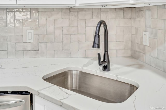 interior details with sink, white cabinetry, dishwasher, and light stone countertops