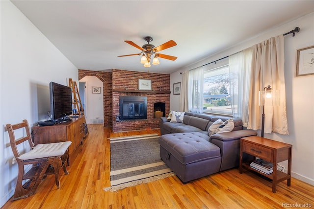 living room featuring a ceiling fan, light wood-type flooring, and a fireplace