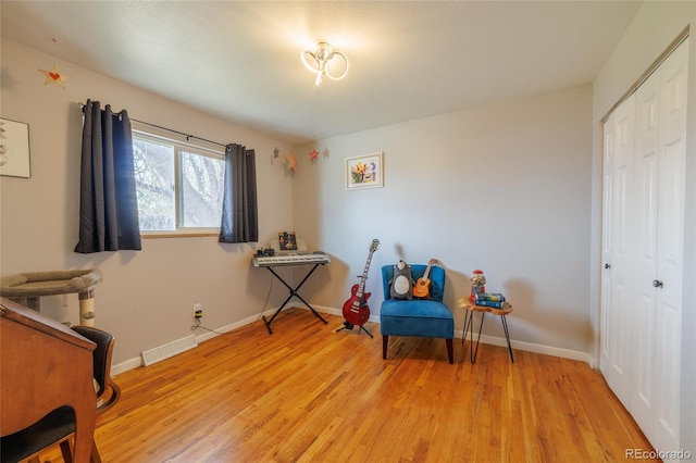 living area featuring baseboards, light wood-type flooring, and visible vents
