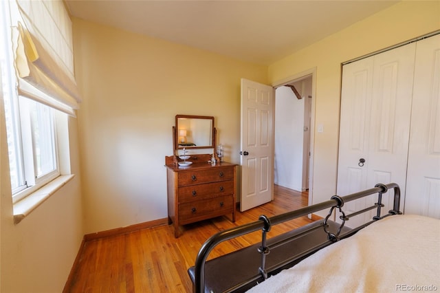 bedroom featuring baseboards, wood finished floors, and a closet