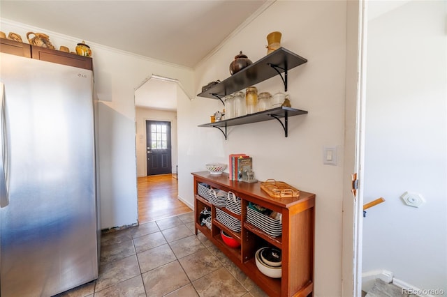 corridor with crown molding, baseboards, and light tile patterned floors