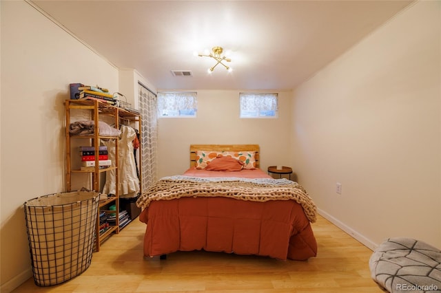 bedroom featuring baseboards, visible vents, and light wood finished floors