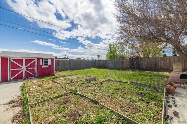 view of yard with an outdoor structure, a storage shed, a fenced backyard, and a vegetable garden