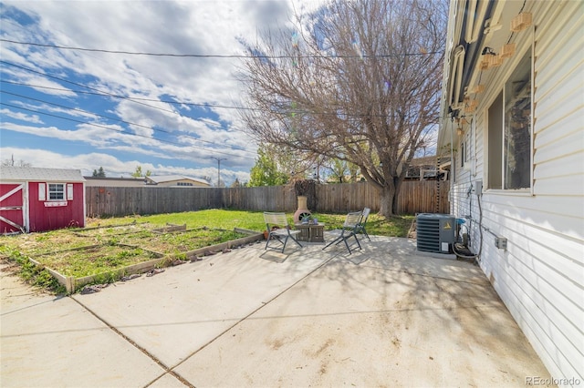 view of patio with a storage shed, a fenced backyard, central AC unit, an outbuilding, and a fire pit